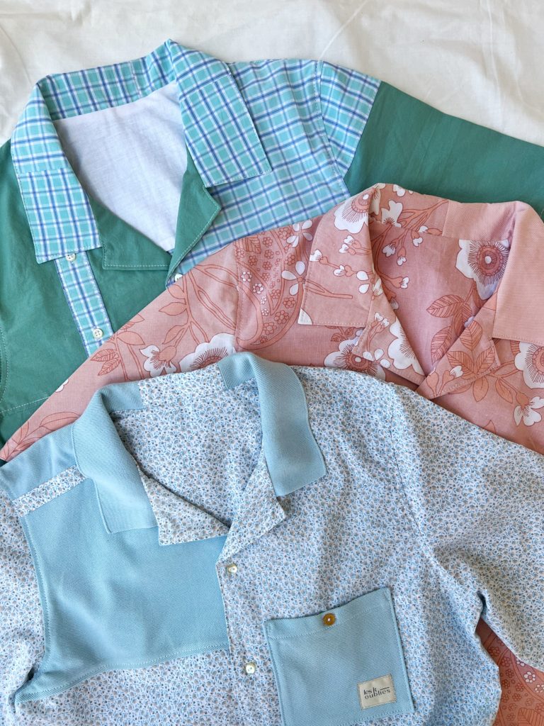 IMG_6393 Upcycling de chemises. Trio de chemises upcyclées, de couleurs verte, rose et bleues, avec des motifs fleuris, positionnées sur un fond blanc.